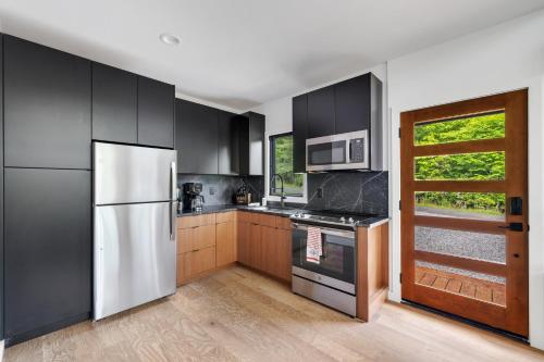 a kitchen with black cabinets and a white refrigerator at Viking Hut Modern Forest Hideaway Fall Dogs in Young Harris