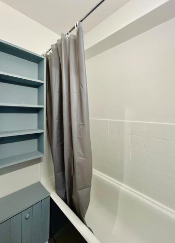 La salle de bains est pourvue d'un rideau de douche et d'une baignoire. dans l'établissement Studio moderne 26 m2 tout confort - 5 couchages - La Foux d'Allos, à Allos