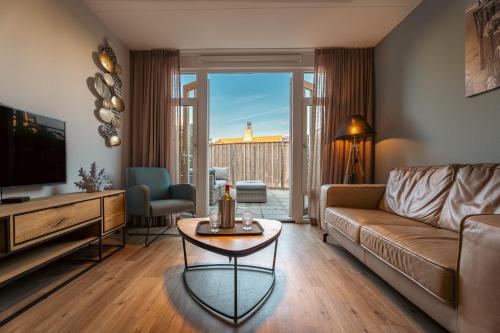 a living room with a couch and a tv at Boutique Resort Schaardijk vakantiewoning in Scharendijke