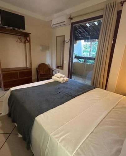a bedroom with a large white bed and a window at Pousada Pangea Tropical in Arraial d'Ajuda