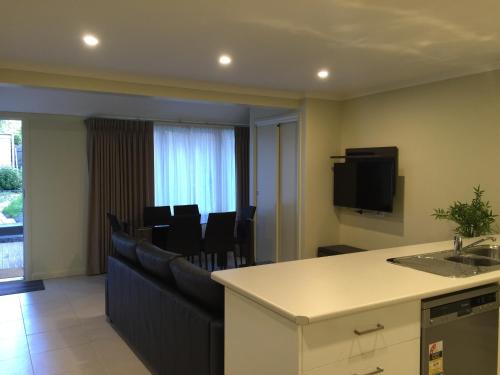 a living room with a bar and a kitchen with chairs at Park Squire Motor Inn & Serviced Apartments in Melbourne