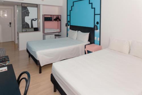 a hotel room with two beds and a mirror at ibis Styles Goiania Marista in Goiânia