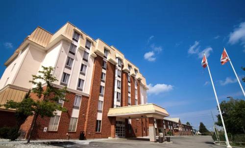 a red and white building with flags in front of it at Waterloo Suites Hotel, Trademark Collection by Wyndham in Waterloo