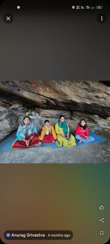 three people are sitting on the ground in a cave at The Chakras Valley Homestay in Binsar