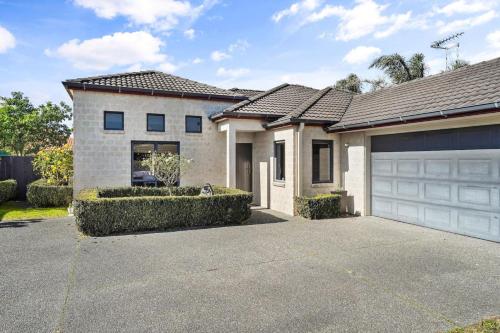 a house with a garage and a driveway at Luxury and Location Beautiful Beach Home in Papamoa