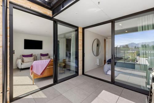 a room with sliding glass doors and a living room at Mountainview Escape | Stylish, BBQ, and Parking in Wanaka