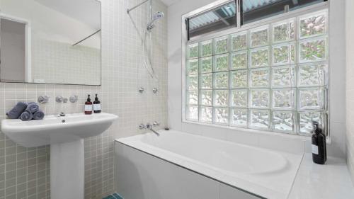 a white bathroom with a sink and a tub and a window at Mountain Breeze Retreat in Smithfield