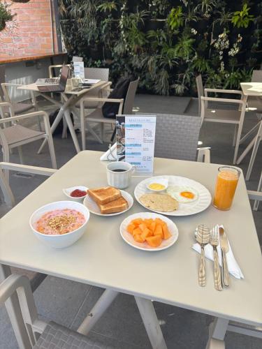 a table with plates of breakfast food on it at Vita Hotel Boutique - Aire Acondicionado & Desayuno in Medellín