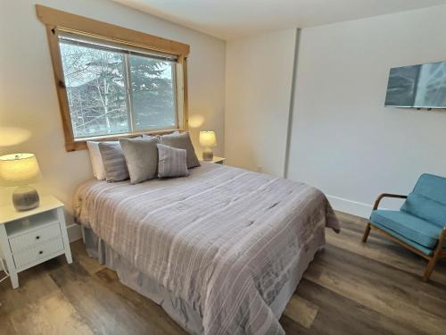 a bedroom with a large bed and a blue chair at Large Modern Driggs Home with Game Room and Jacuzzi! in Driggs