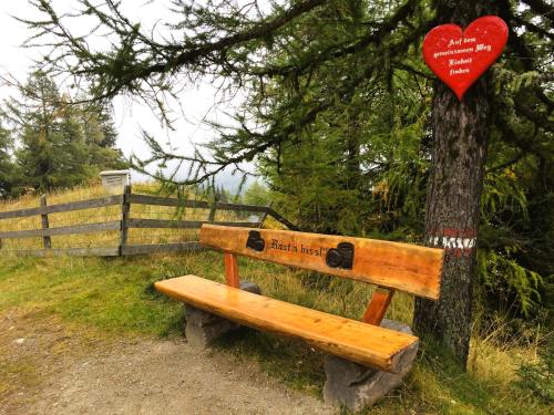 a wooden bench with a heart sign on a tree at Design-Apartment Katschi - Entspannung auf 1641m Höhe in Katschberghöhe