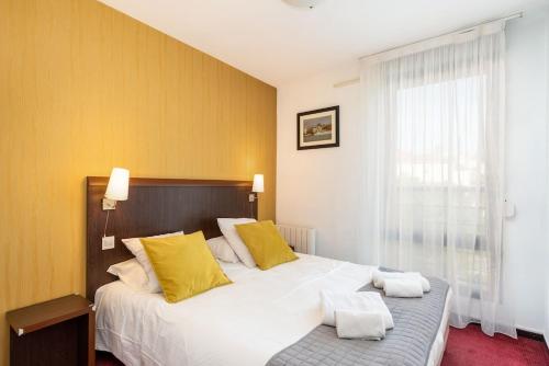 - une chambre avec un grand lit blanc et des oreillers jaunes dans l'établissement le Valmy avec balcon, à Lyon