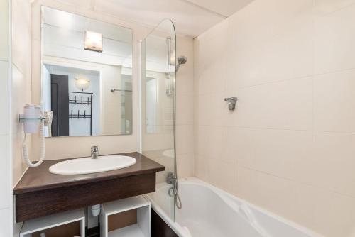 une salle de bain blanche avec un lavabo et une douche dans l'établissement le Valmy avec balcon, à Lyon