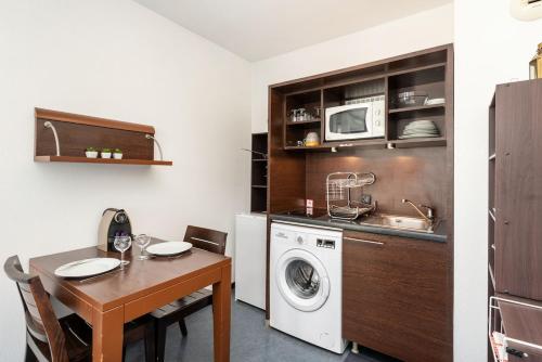 une cuisine avec une table et une machine à laver dans l'établissement le Valmy avec balcon, à Lyon