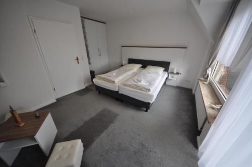 a small white bedroom with a bed and a table at Haus am Binnensee in Fehmarn