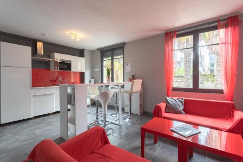 Il comprend un salon doté d'un mobilier rouge et une cuisine. dans l'établissement T3 ensoleillé le Vignemale, à Lourdes