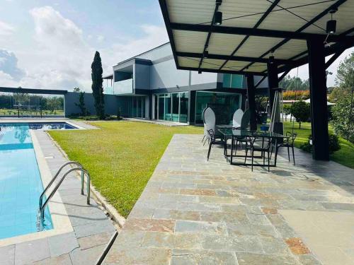 a patio with a table and chairs next to a pool at Country house near the airport and Medellin in El Retiro