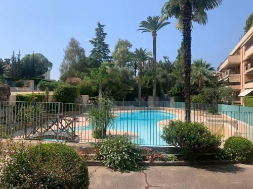 une piscine avec une clôture et des palmiers dans l'établissement Appt 2ch 90m2 avec terrasse 40m2, piscine et tennis, à Cannes