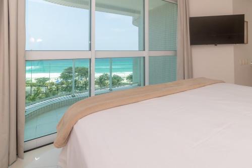 Un dormitorio con una cama blanca y una ventana grande. en Apartment Ocean View, en Río de Janeiro