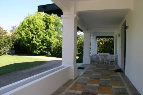 une terrasse couverte d'une maison avec une table et des chaises dans l'établissement grande maison de famille prés d'Hossegor, à Bénesse-Maremne