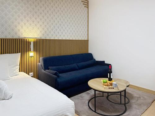 un salon avec un canapé bleu et une table dans l'établissement Le Nid - Paris - Le Blanc Mesnil, au Blanc-Mesnil
