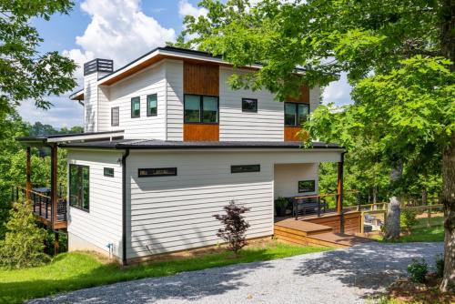 a white house with a porch and a deck at Level Up 3br Fall Retreat, Hot Tub, Firepit Dogs in Young Harris