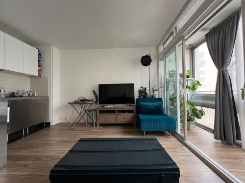 un salon avec une chaise bleue et une télévision dans l'établissement Bright studio, à Vanves