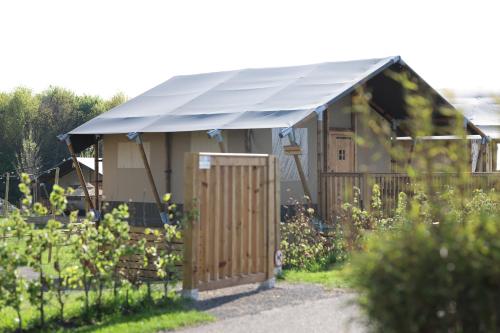 a small building with a blue roof in a garden at Safari Lodges Premium in Nieuwe Wetering