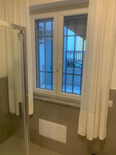 a bathroom with a shower and two windows at Luciano Home in Gonnesa