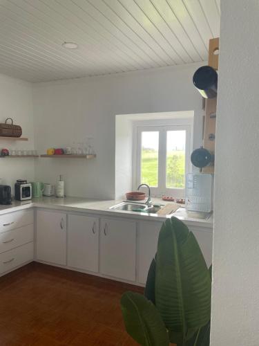 a white kitchen with a sink and a window at House In The Valley in Algarvia