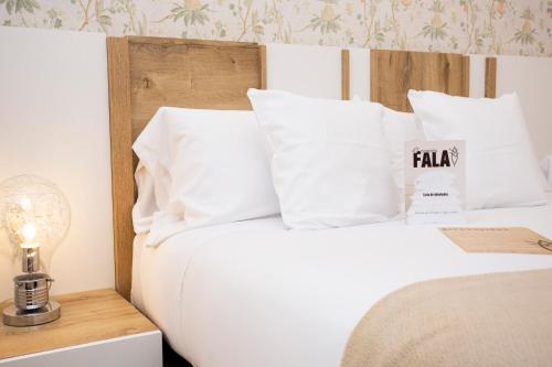 a bed with white pillows and a table with a lamp at O Camiño Fala Hotel in Mazaricos