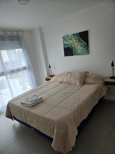 a bedroom with a large bed with a painting on the wall at Departamento Charlone temporal in Bahía Blanca