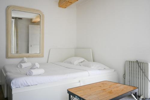 un lit blanc avec un miroir et une table dans l'établissement Bright and Cosy studio apartment in Republique Paris, à Paris