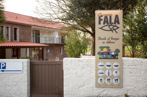 a sign in front of a fence with a building at O Camiño Fala Hotel in Mazaricos