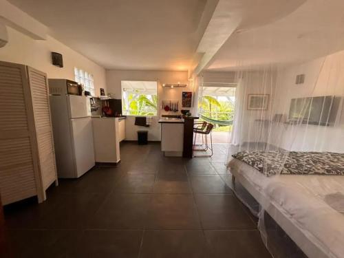 ein Zimmer mit einem Bett und einer Küche mit Kühlschrank in der Unterkunft Studio confortable à Petit-Bourg avec terrasse 30 m² in Petit-Bourg