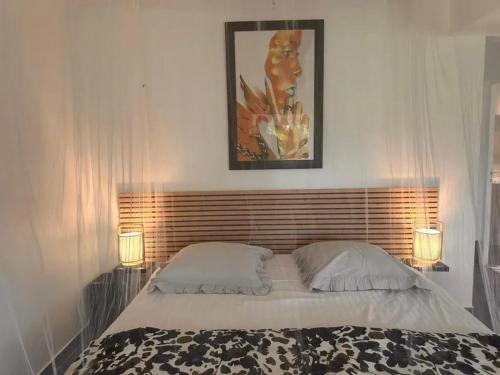 ein Schlafzimmer mit einem Bett mit zwei Lampen und einem Bild in der Unterkunft Studio confortable à Petit-Bourg avec terrasse 30 m² in Petit-Bourg