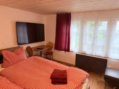 a bedroom with a bed and a flat screen tv at Vintage Apartment By Apartments Capricorn in Gsteigwiler
