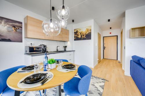 a kitchen and dining room with a table and blue chairs at ReVital Mechelinki by Homeprime Parking Free in Mechelinki