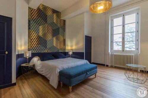 a bedroom with a bed with a blue ottoman and a window at Château de puydaniel in Puydaniel