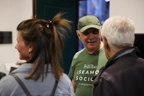 a man in a green shirt standing between two people at Hostel Bosmi Bed&Language Liguria in Sori