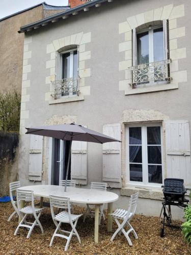 - une table et des chaises avec un parasol en face d'une maison dans l'établissement Gite chez Odile maison entiere 6 personnes, à Cellettes