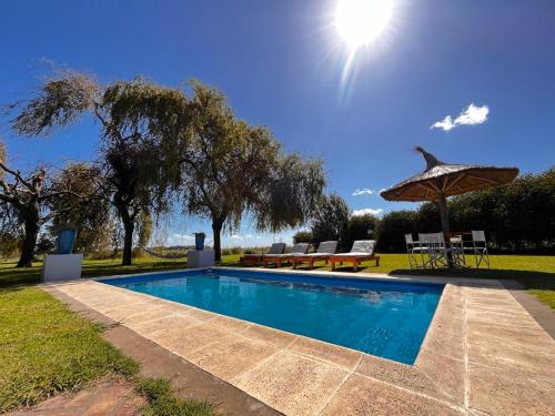 a swimming pool in a yard with a umbrella at Brisas de Brandsen, Chacras con estilo in Loma Verde