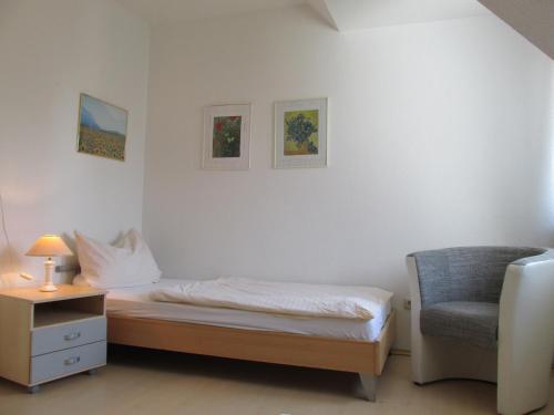 a bedroom with a bed and a chair and a lamp at Albatros-Herber in Dorum Neufeld