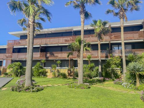 a building with palm trees in front of it at Poolfront Apartment Close to Beach in Tamaris