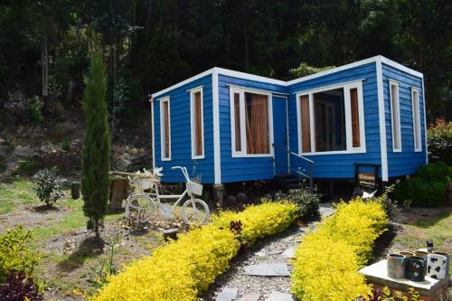 a blue tiny house with a bike in a yard at Aldea Fuquenense in Fúquene