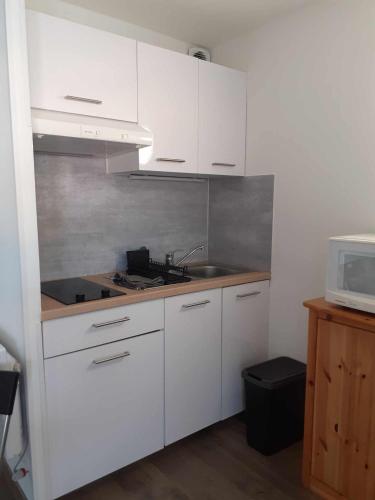 une cuisine avec des armoires blanches, un évier et un micro-ondes dans l'établissement 005 ipanema L'esCapAgde, au Cap d'Agde