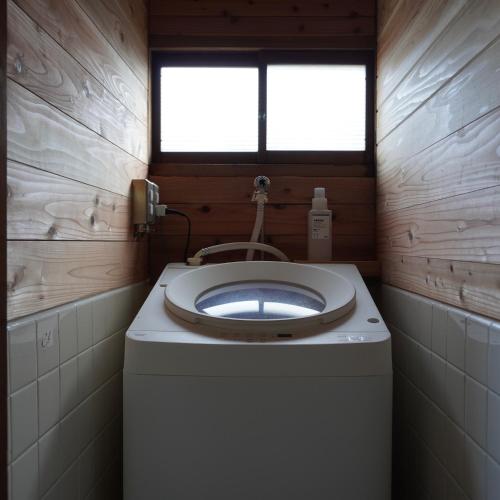 a small bathroom with a toilet and a window at suo 椿の島の宿 in Oshima