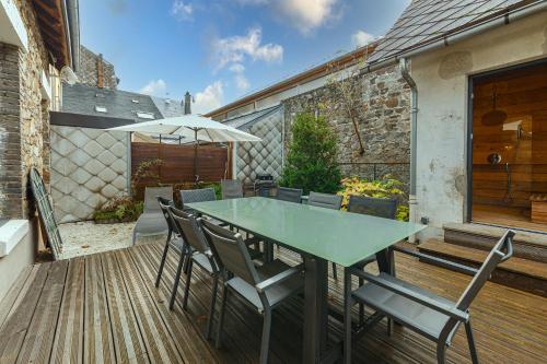 a table with chairs and an umbrella on a deck at Le Cosy de Claire in La Bourboule