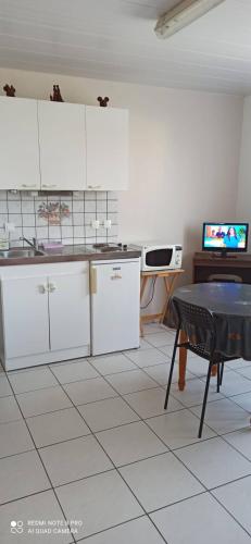 Il comprend une cuisine avec des placards blancs, une table et une télévision. dans l'établissement Maison proche parc Disney, à Montry