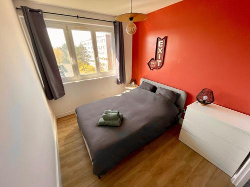 a bedroom with a bed with an orange wall at Appartement 3 Chambres & Dernier étage in Amiens