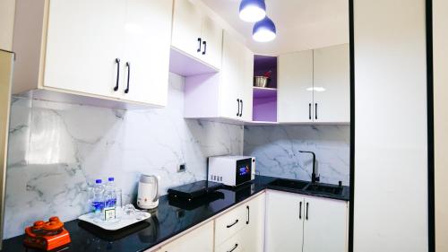 a kitchen with white cabinets and a black counter top at Brighton Guest House and Cafe in Addis Ababa